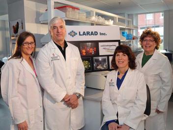 Ohio State University scientists standing in front of a poster for LARAD Inc.