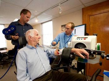 patient with arm strapped to medical device being attended by physician