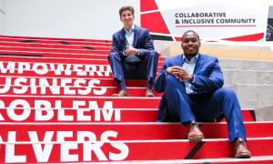 UC business students Patrick McNamara and Sharif Johnson sit on printed steps that state "Empowering Business Problem Solvers" inside the Lindner College of Business.